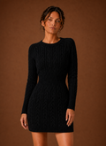 Front view of women's cable knit long-sleeve mini sweater dress on plain background