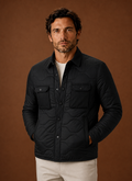 Front view of men's black quilted shirt jacket on neutral background