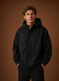 Front view of a men's black hooded windbreaker jacket on a neutral background