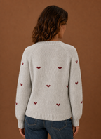 Back view of women's knit pullover displaying heart pattern across the back