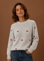 Front view of women's light grey knit sweater with crew neckline and allover heart print