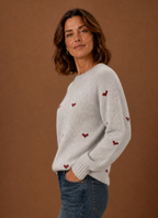 Side profile of women's heart print sweater showing long sleeve and relaxed fit