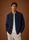 Front view of men's cable knit cardigan with button-front closure on a mannequin